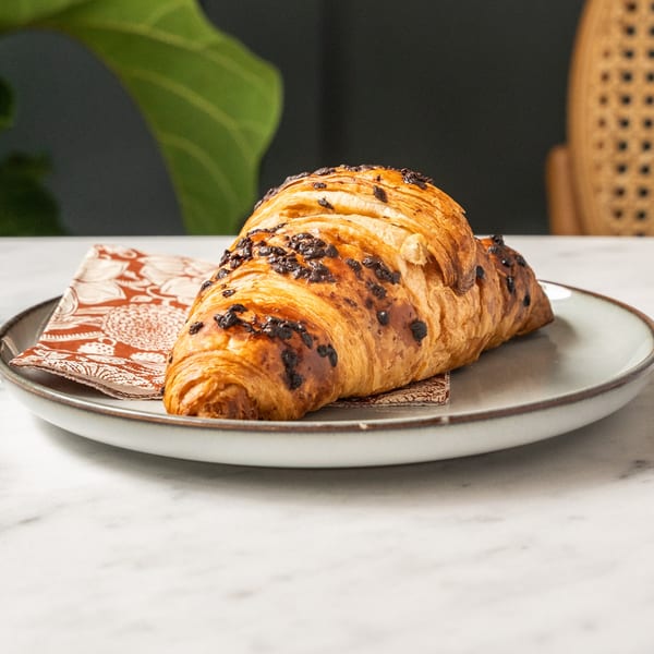 A golden-brown chocolate croissant on a patterned napkin and white plate at Café Taureau.