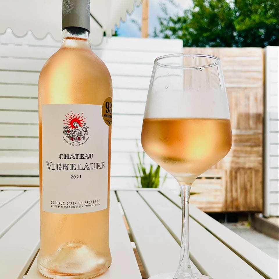 A chilled bottle and glass of Chateau Vignelaure rosé wine on a white outdoor table.